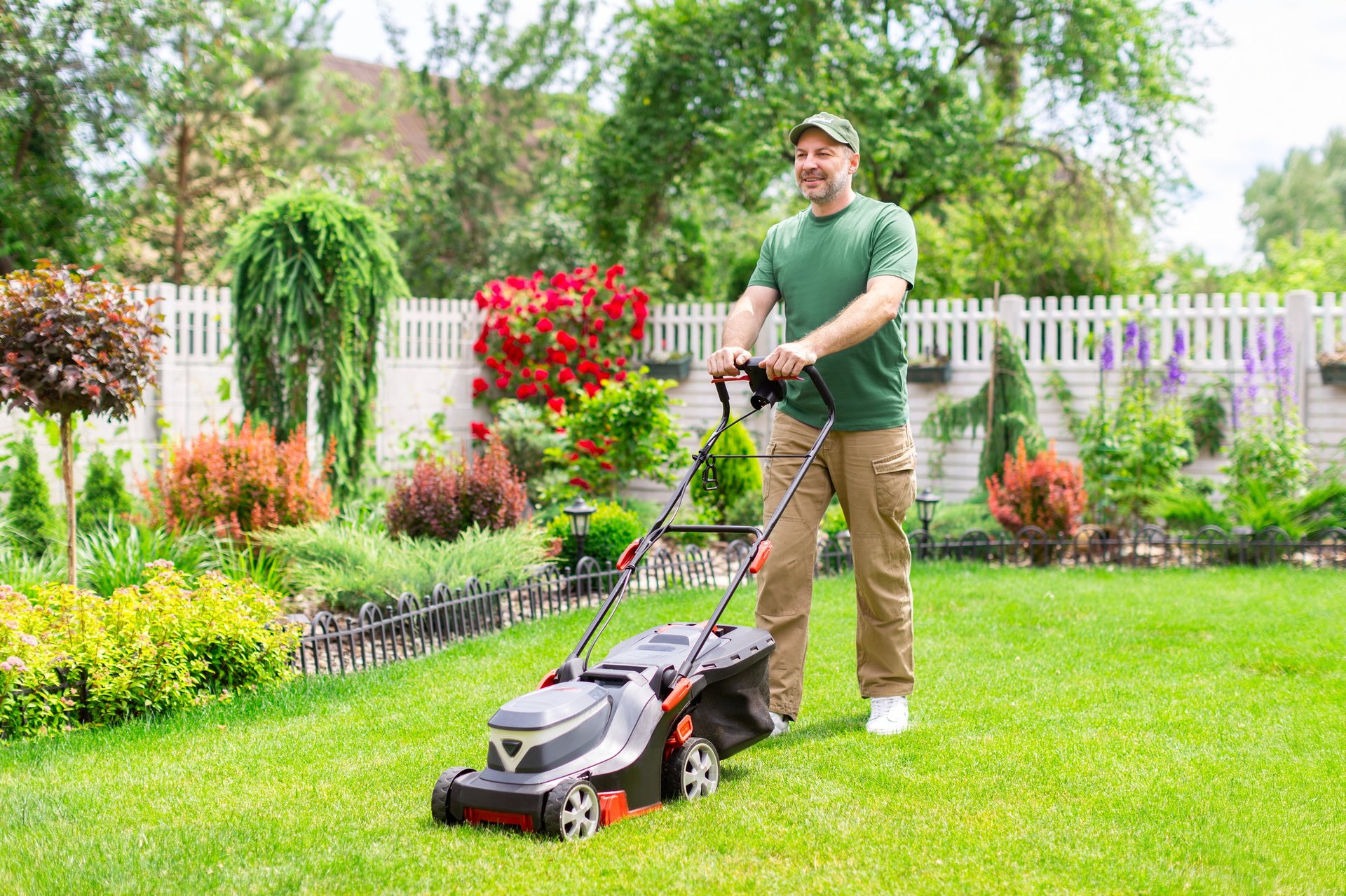 Middle aged man mowing the lawn in backyard